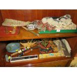 TWO SHELVES OF DECORATIVE AND TOURIST WARE INCLUDING TEXTILES, SOUVENIR PIPE, CONCERTINA FAN AND