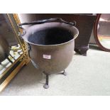 A BEATEN BRASS VESSEL OR CAULDRON WITH WROUGHT METAL LEGS AND HANDLE