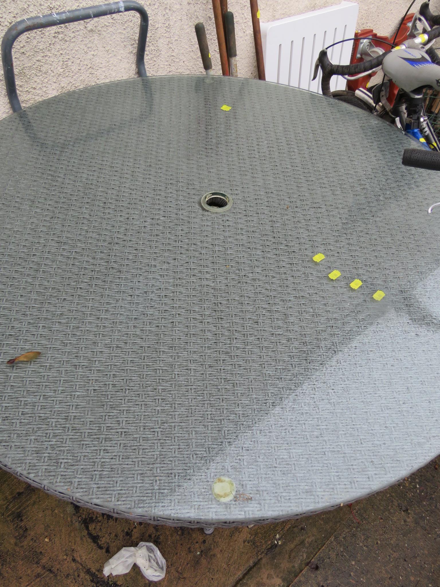 A PATIO TABLE WITH GLASS TOP AND PARASOL