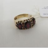 9 CARAT GOLD RING SET WITH THREE LARGE GARNETS AND FIVE SMALL GARNETS (ONE ABSENT), BRITISH