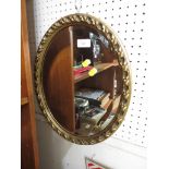 AN OVAL BEVELLED EDGE WALL MIRROR IN A GILT EFFECT FRAME