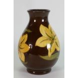 Walter Moorcroft vase decorated with Bermuda Lily on brown ground: height 20cm.