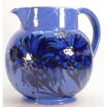 William Moorcroft jug decorated in the Cornflower design on powder blue ground: Height 19cm.