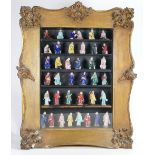 A collection of 19th Century miniature Porcelain Mud Man figures: In various poses in gilt frame,
