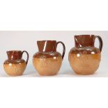 A collection of Doulton Lambeth embossed Stoneware items to include: Graduated set of 3 jugs