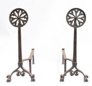A pair of Arts and Crafts wrought iron Firedogs: With Gothic rose window tracery finials.