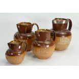 A collection of Doulton Lambeth embossed Stoneware items to include: Graduated set of 4 jugs