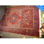 Modern Iranian red ground rug having central medallion, the blue border decorated with stylised
