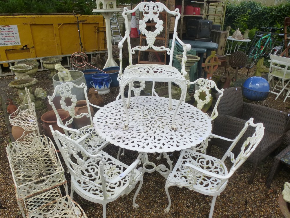 A vintage ornate garden set to include 5 carver chairs and a round table