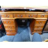 A reproduction leather revolving desk chair and a yew wood pedestal desk having eight drawers