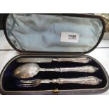 A silver case fruit knife, spoon and fork with weighted handles and ornate embossed design with