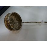 A white metal ladle with an embossed design to the bowl and a twisted bone handle