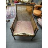 An antique mahogany bergere armchair on turned front legs