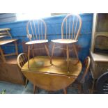 Light Ercol golden elm circular drop flag table and set of four hoop and stick back dining chairs