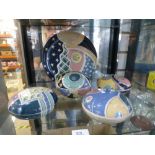 A shelf of pottery art to include a plate and four lidded dishes