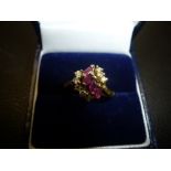 Yellow metal dress ring set with diamond chips and rubies, size O