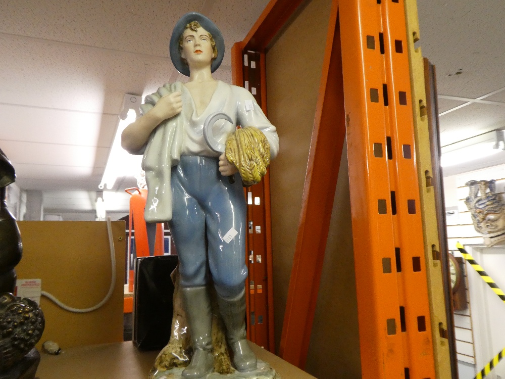 A porcelain figure of a man holding a scythe and corn, AF