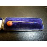 Yellow metal stick pin, with coral bead, in leather case
