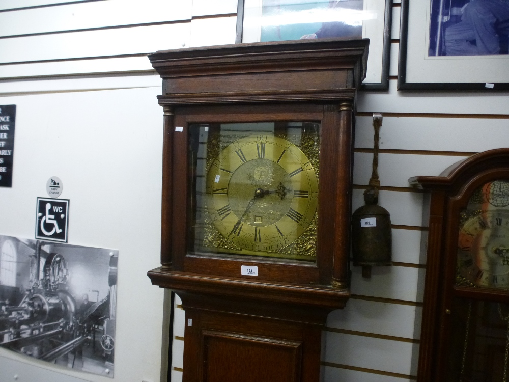 A dark oak grandfather clock with a brass dial