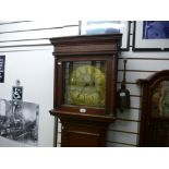 A dark oak grandfather clock with a brass dial