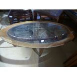 A vintage oval coffee table having inset glass top