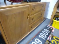 An Ercol medium oak sideboard, having three central drawers, 155cms