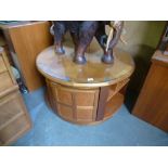 A Nathan round coffee table having cupboards and shelves