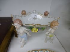 A pair of Coalport plates and a Dresden bon-bon dish, supported by cherubs