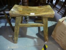 An old carved stool in splayed supports