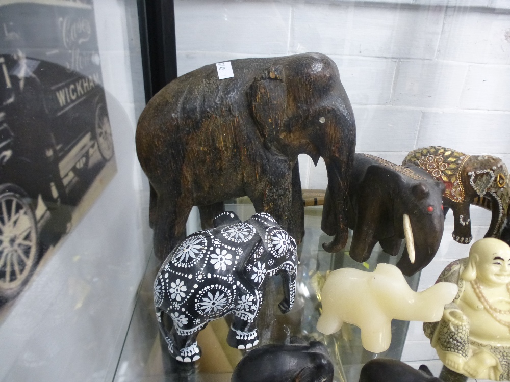 A shelf of carved elephant figures, mostly wood, etc