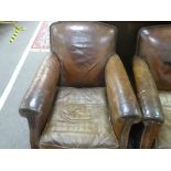 A pair of old brown leather Club armchairs on bun feet
