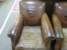 A pair of old brown leather Club armchairs on bun feet