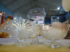 A glass bowl with swan decoration, with another bowl and two long stemmed glasses