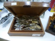 A collection of souvenir spoons in a wooden lidded box.