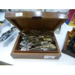 A collection of souvenir spoons in a wooden lidded box.