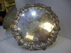 A large silver decorative plate of circular form with ornate edges and three pretty decorative feet.