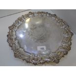 A large silver decorative plate of circular form with ornate edges and three pretty decorative feet.