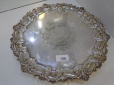 A large silver decorative plate of circular form with ornate edges and three pretty decorative feet.