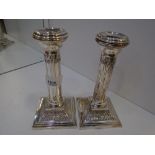 A pair of silver Edwardian decorative candlesticks on stepped square bases with ornate floral
