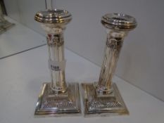 A pair of silver Edwardian decorative candlesticks on stepped square bases with ornate floral