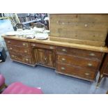 An old pine dresser base, having central cupboard flanked by drawers on turned feet, length 219cms