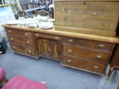 An old pine dresser base, having central cupboard flanked by drawers on turned feet, length 219cms