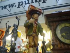 A carved wooden figure of a clock seller