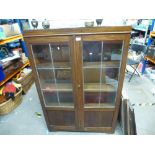 A dark stained oak bookcase with leaded glass doors