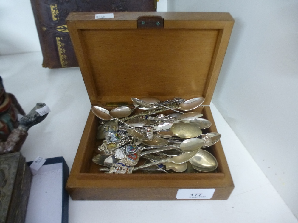 A collection of souvenir spoons in a wooden lidded box.