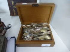 A collection of souvenir spoons in a wooden lidded box.