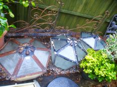 A set of three vintage metal and glass hexagonal lanterns with a set of three wrought iron corner