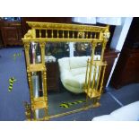 A late Victorian gilt overmantel mirror having side shelves iwth turned suppoorts and bevelled glass