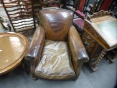 A pair of old brown leather Club armchairs on bun feet