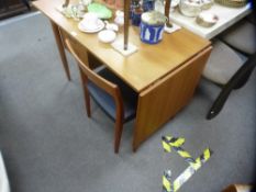 A vintage teak desk, having two drawers and side flap on turned legs, with a single teak chair by